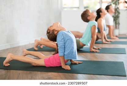 Little girl with family practicing yoga on mat in fitness studio - Powered by Shutterstock