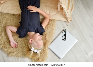 Little Girl Fell Asleep On The Floor In Her Room Next To A Laptop.