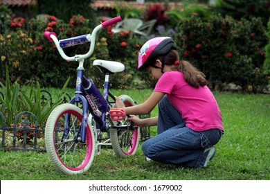 Little Girl Fixing A Bike On A Home Front Yard
