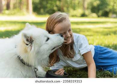 Niña pequeña en el parque forestal caminando jugando con su perro blanco samoyado tiempo de verano estacional