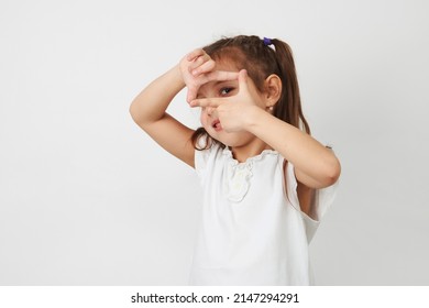 Little Girl Framing Photography Over White Background. Portrait Of Child Girl Making Photo Frame With Hands