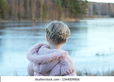 A Little Girl With Franch Milkmaid Braid In Her Hair. Looking Over A Frozen River In Winter.