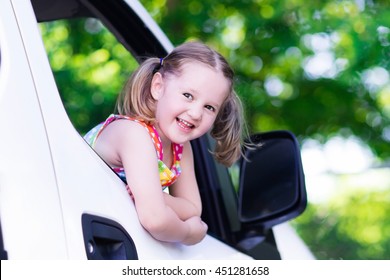 Little Girl With Funny Pigtails Watching Out Of Car Window Sitting On Front Driver Seat During A Break On A Family Vacation Road Trip On Summer Day. Child In White Minivan. Traveling By Car With Kids.