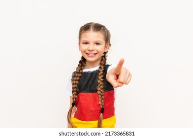 A little girl with a German flag on a T-shirt, with long hair braided in pigtails on a white isolated background. Language courses for children. Space for copying.