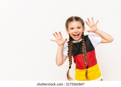 A little girl with a German flag on a T-shirt, with long hair braided in pigtails on a white isolated background. Language courses for children. Copy space.