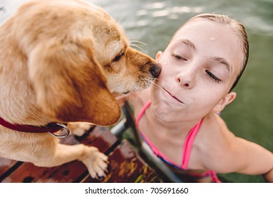 Little Girl Getting Out Of Water While Dog Licking Her Face