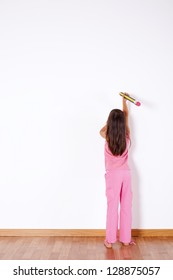 Little girl with a giant pencil writing on the wall