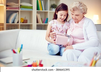 Little girl giving a gift box to her grandmother - Powered by Shutterstock