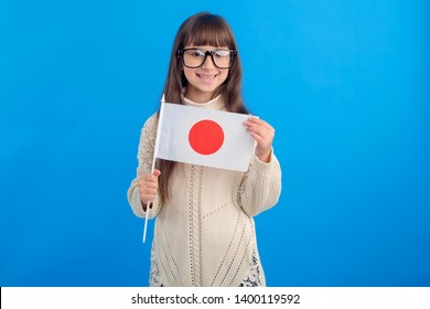 Little girl in glasses with the flag of Japan on a blue background. Education abroad. Learn Japanese.