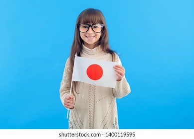 Little Girl In Glasses With The Flag Of Japan On A Blue Background. Education Abroad. Learn Japanese.