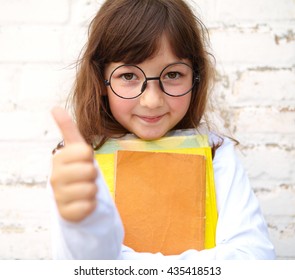 Little girl with glasses holding a books in their hands