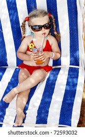 Little Girl In Glasses And Red Bikini Drink Orange Juice.