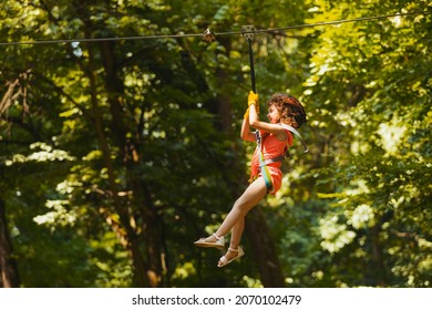 The Little Girl Goes Down The Zipline In The Park