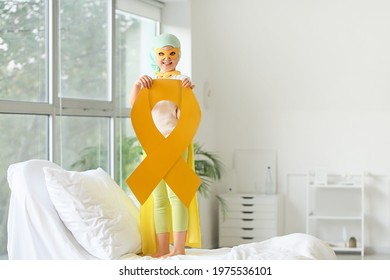Little girl with golden ribbon wearing superhero costume in clinic. Childhood cancer awareness concept - Shutterstock ID 1975536101