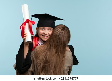 Little Girl Graduate Celebrating Graduation. Child Wearing Graduation Cap And Ceremony Robe Holding Certificate. Mom Hugs And Congratulations Daughter On Graduation. Successfully Complete Course Study