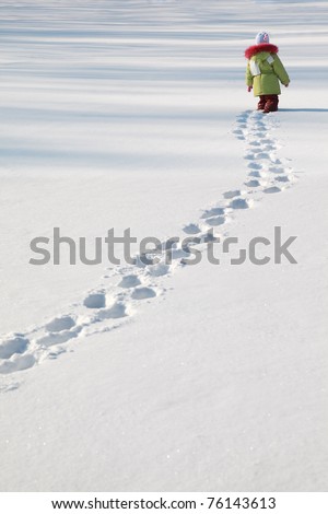 little girl in green jacket walking on snow, footprints in snow, behind