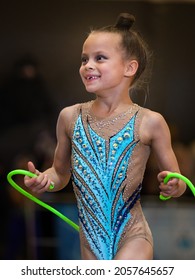 Little girl gymnast in beautiful blue leotard walking from performance place and smiling