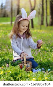 Little girl happy collecting Easte eggs in grass - Shutterstock ID 1698857104
