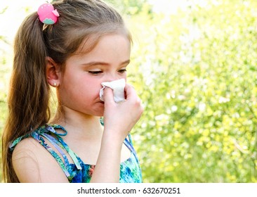 Little girl has allergy to spring blossoming and blowing her nose outdoor