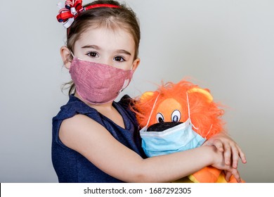 Little girl has fabric mask protect herself from Coronavirus COVID-19, child with a mask for safety.Studio shot with her toy in mask.