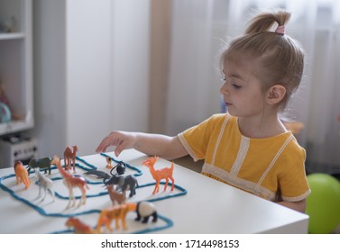 Little Girl Has A Fun Time Playing With Toy Animal Figures.Child Learning Animals. Early Education And Development.