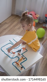 Little Girl Has A Fun Time Playing With Toy Animal Figures.Child Learning Animals. Early Education And Development.