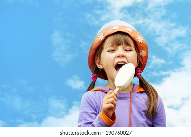 Little Girl In Hat Eating Ice Cream On A Background Of Sky