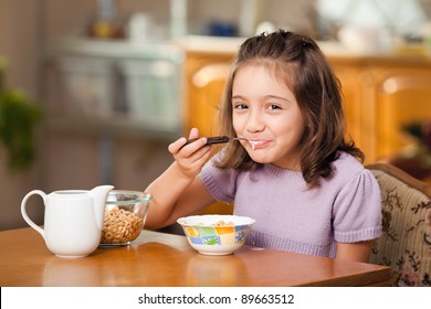 little girl having breakfast: cereals with milk