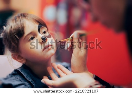 
Little Girl Having a Face Paint Moment at her Birthday Party. Cute, adorable toddler kid having fun with creative activity
