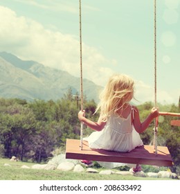 Little girl having fun on a swing outdoor 
