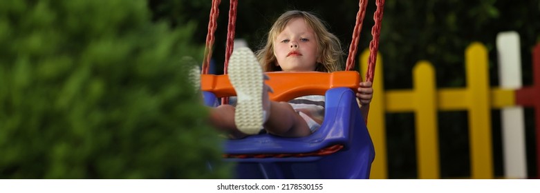 Little Girl Having Fun On Swing On Playground In Park Alone