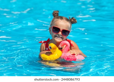 Little girl having fun on vacation at the hotel pool. Colorful vacation concept. Summer outdoor activity during family vacation in tropical resort. Beach and water toys. Sun protection. - Powered by Shutterstock