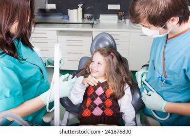 Little Girl Is Having Her Teeth Examined By Dentist.Little Girl Sitting And Smiling In The Dentists Office. Child Not Afraid Of Dentist