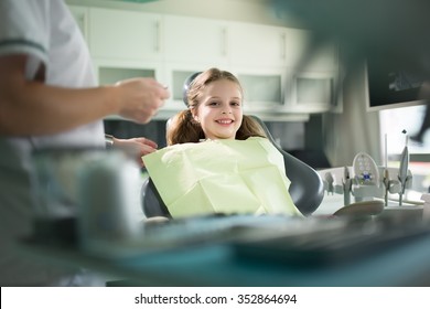 Little girl is having her teeth examined by dentist.Little girl sitting and smiling in the dentists office.Child not afraid of dentist.Dentist gives the child patient advice on dental care and hygiene