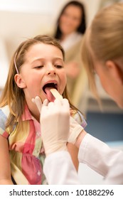 Little Girl Having Throat Examination With Tongue Depressor