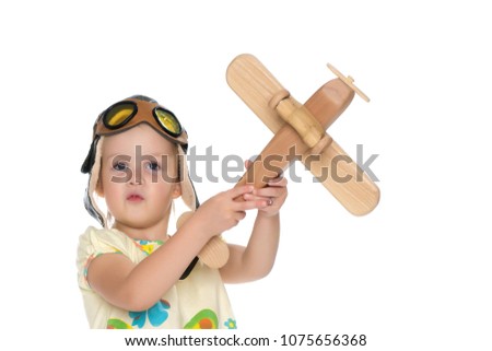 Little girl in helmet pilot with wooden plane in hand. The concept of family happiness, the embodiment of a dream, a love of travel. Isolated on white background.