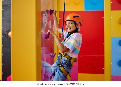 Little girl in helmet poses on climbing wall - Powered by Shutterstock