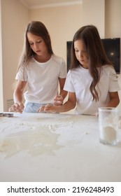 Little Girl Is Helping To Bake In A Messy Kitchen.