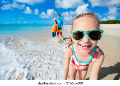 Little girl and her family father and brother enjoying beach vacation in Caribbean