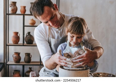 Little girl with her father working with clay on potter's wheel. Selective focus. - Powered by Shutterstock