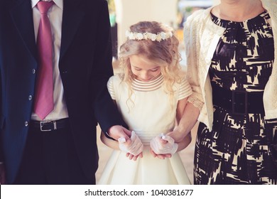 Little Girl in her First Communion Day with Her Father and mother. - Shutterstock ID 1040381677