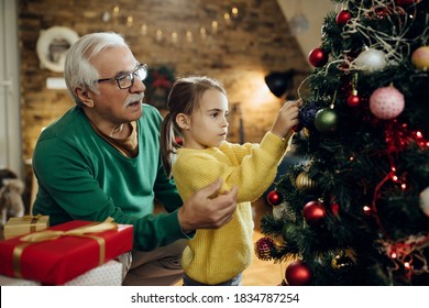 Little girl and her grandfather decorating Christmas tree in the living room. - Powered by Shutterstock