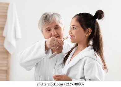 Little girl and her grandma brushing teeth in bathroom