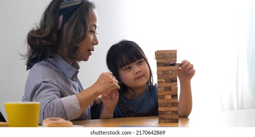 Little Girl With Her Grandma Playing Jenga Game At Home
