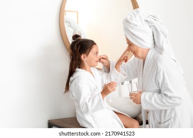 Little girl and her grandma touching each other's noses in bathroom