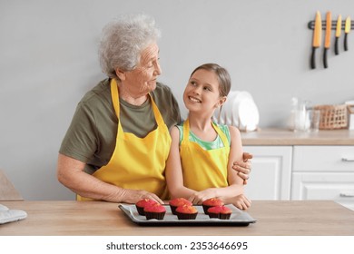 Little girl and her grandmother with prepared muffins in kitchen - Powered by Shutterstock