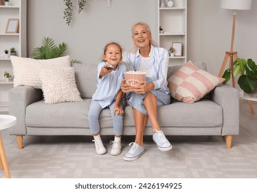 Little girl with her grandmother watching TV at home - Powered by Shutterstock