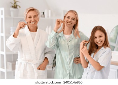 Little girl with her mom and grandmother brushing hair in bathroom
