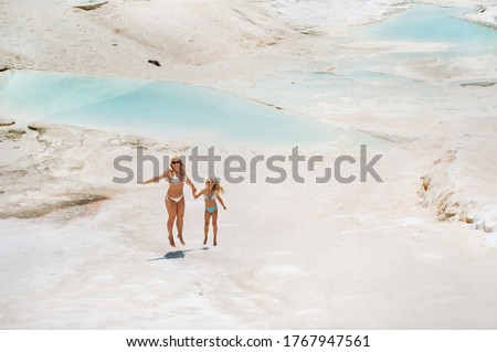 a little girl with her mother in bathing suits and sunglasses on a White mountain, a Family on a Sunny summer day on another planet, Pamukkale, Turkey