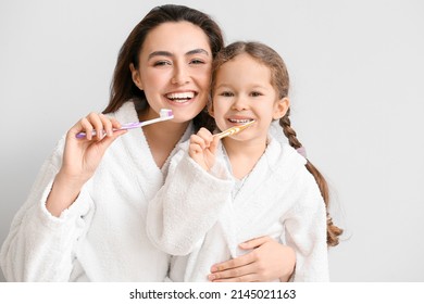 Little girl with her mother brushing teeth on light background - Powered by Shutterstock